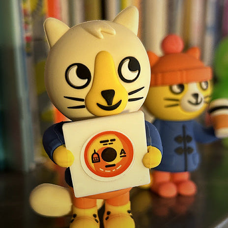 Toy figure of a cat character holding a vinyl record with interchangeable lables. 